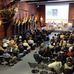 eine voll besetzte Bestuhlung im Galeonsfigurensaal des Altonaer Museums mit Podiumsdiskussion vorn auf einer Bühne