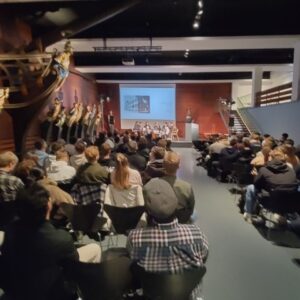 Schüler sitzen vor Publikum auf einer Bühne und diskutieren