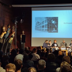 Schüler sitzen vor Publikum auf einer Bühne und diskutieren